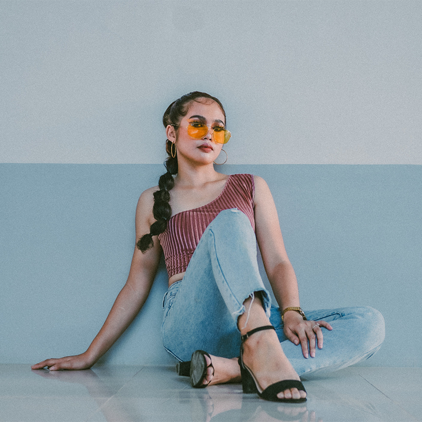 Square a woman sits against a wall posing for a picture.